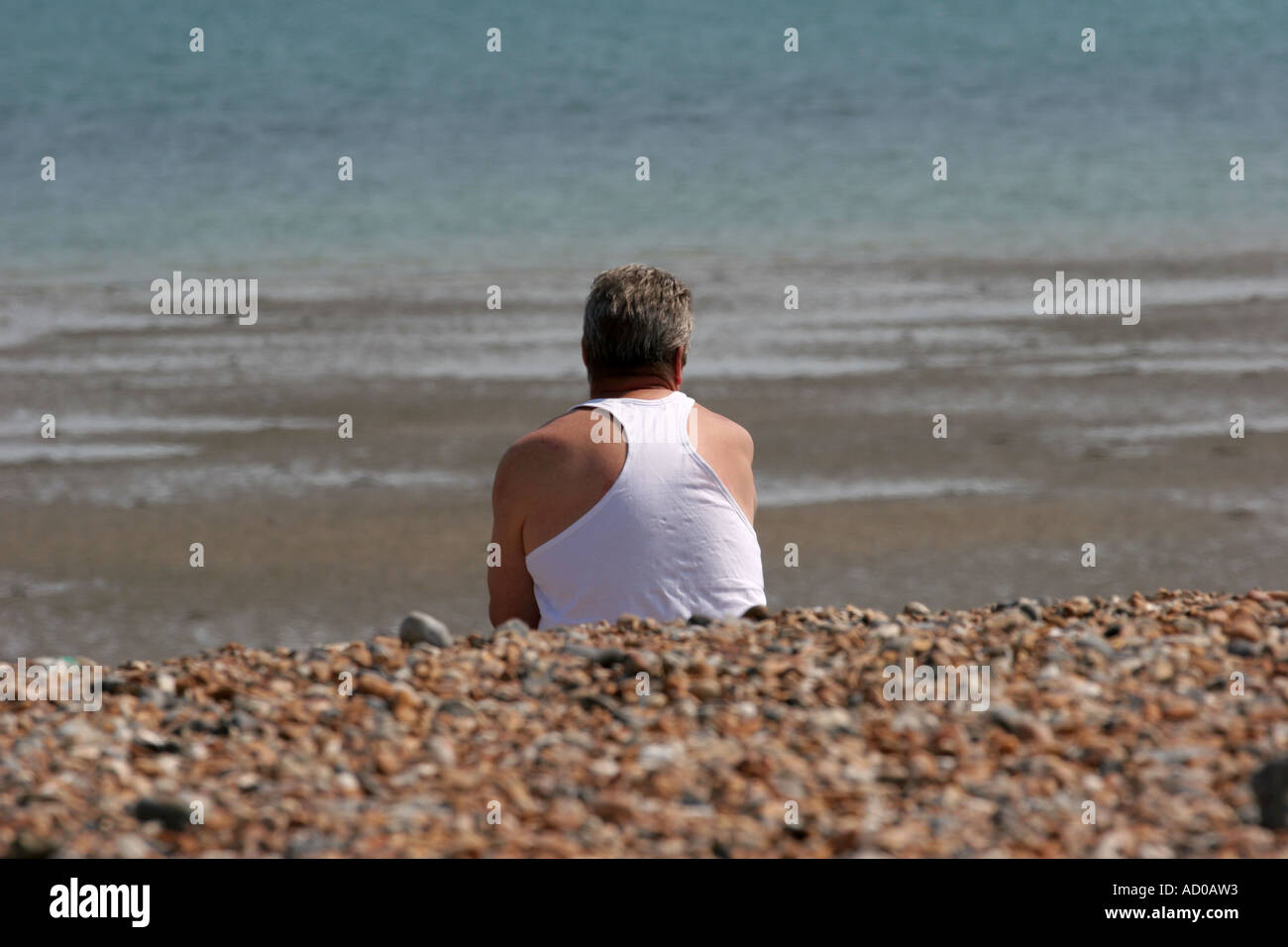 wistful man sitting on beach Stock Photo