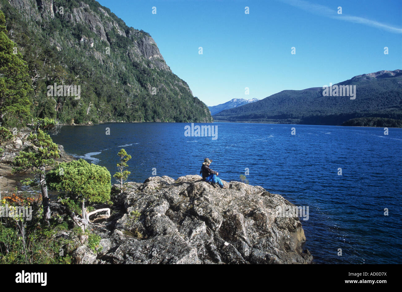 Trekker sitting on rocks looking at view on shore of Lake Paimun, Lanin National Park, Neuquen Province, Argentina Stock Photo