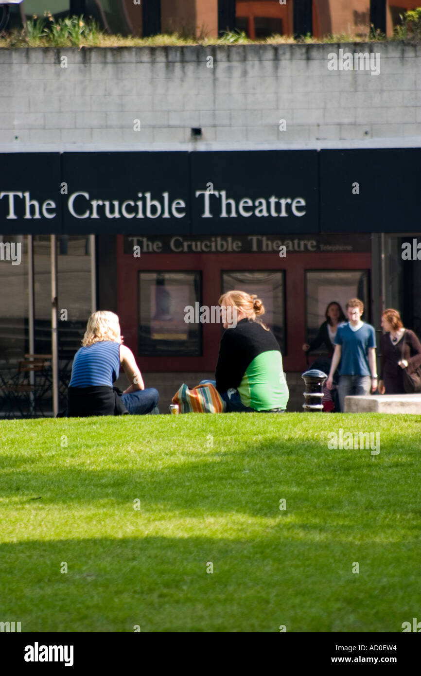 Young women chatting on grass outside The Crucible Theatre Sheffield Stock Photo