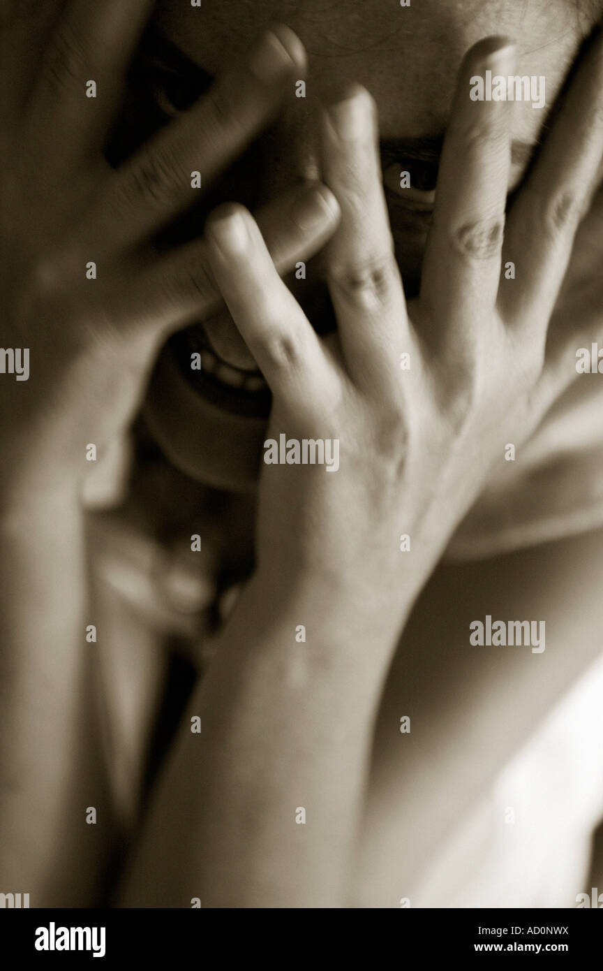woman peeks maniacally through the spread fingers of her hands Stock ...