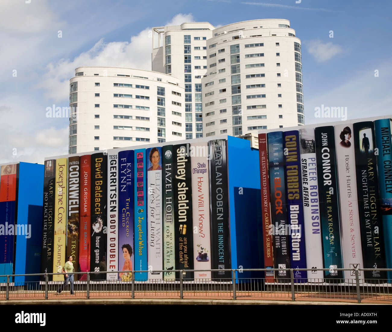 Woman walking past representation of large books on shelf the facade of the central library Cardiff Wales UK Stock Photo