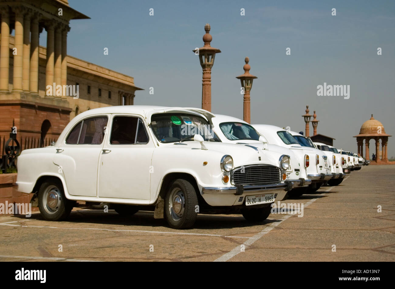 Horizontal view of a row of white Ambassador cars in perfect condition parked outside the government buildings on Raisina Hill. Stock Photo