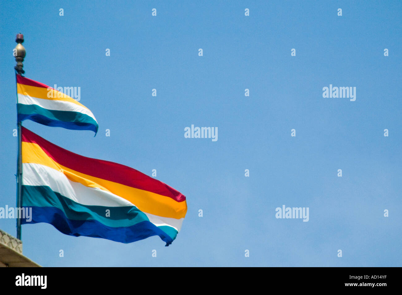 Horizontal close up of the Rajasthani (panchranga) flag flying at full mast against a bright blue sky. Stock Photo