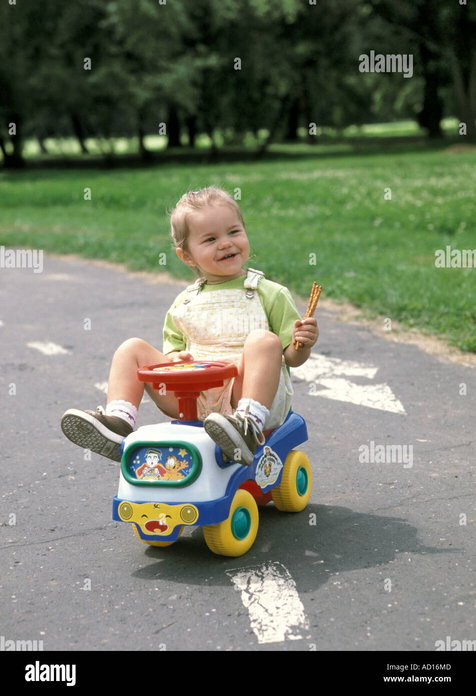 baby girl sitting on toy car in park Stock Photo Alamy