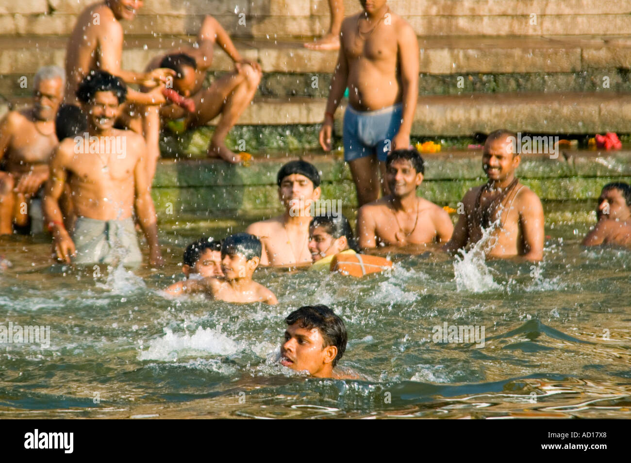 Horizontal wide angle of lots of Indian men swimming and bathing at Ahilyabai Ghat, the mens Ghat, alongside the river Ganges. Stock Photo