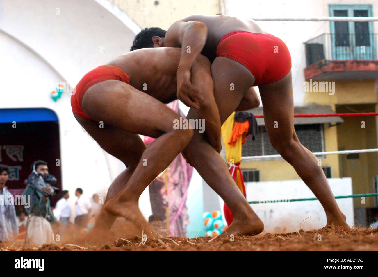 ASB73108 Two South Asian Indian men in red shorts grappling in wrestling sport on red sand sports arena in Bombay India Asia Stock Photo