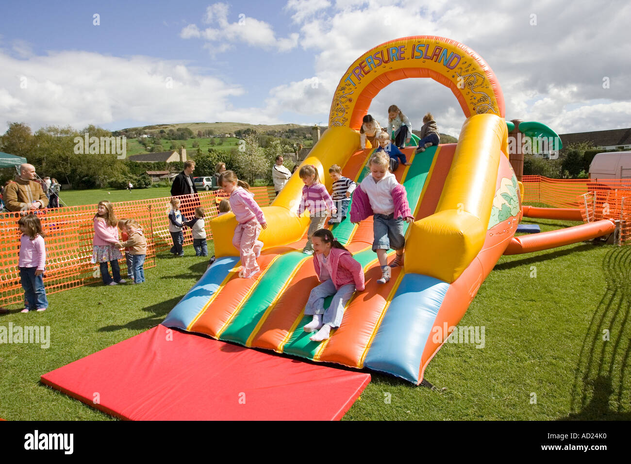 Children enjoying bouncy castle and slide at MayDay fair Woodmancote Gloucestershire UK Stock Photo
