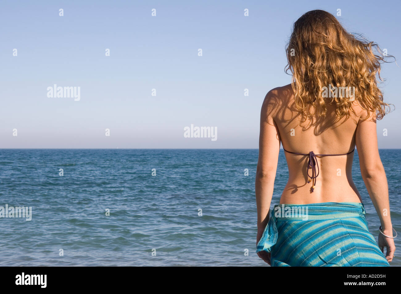 Young woman stood looking out to sea Stock Photo