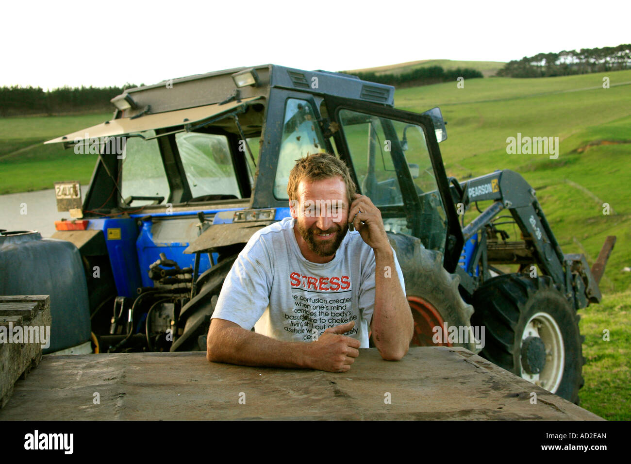 West Coast farmer Mark Woodcock uses a mobile phone whilst he refills his  tractor at Potou Kaipara harbour Northland NZ Stock Photo - Alamy
