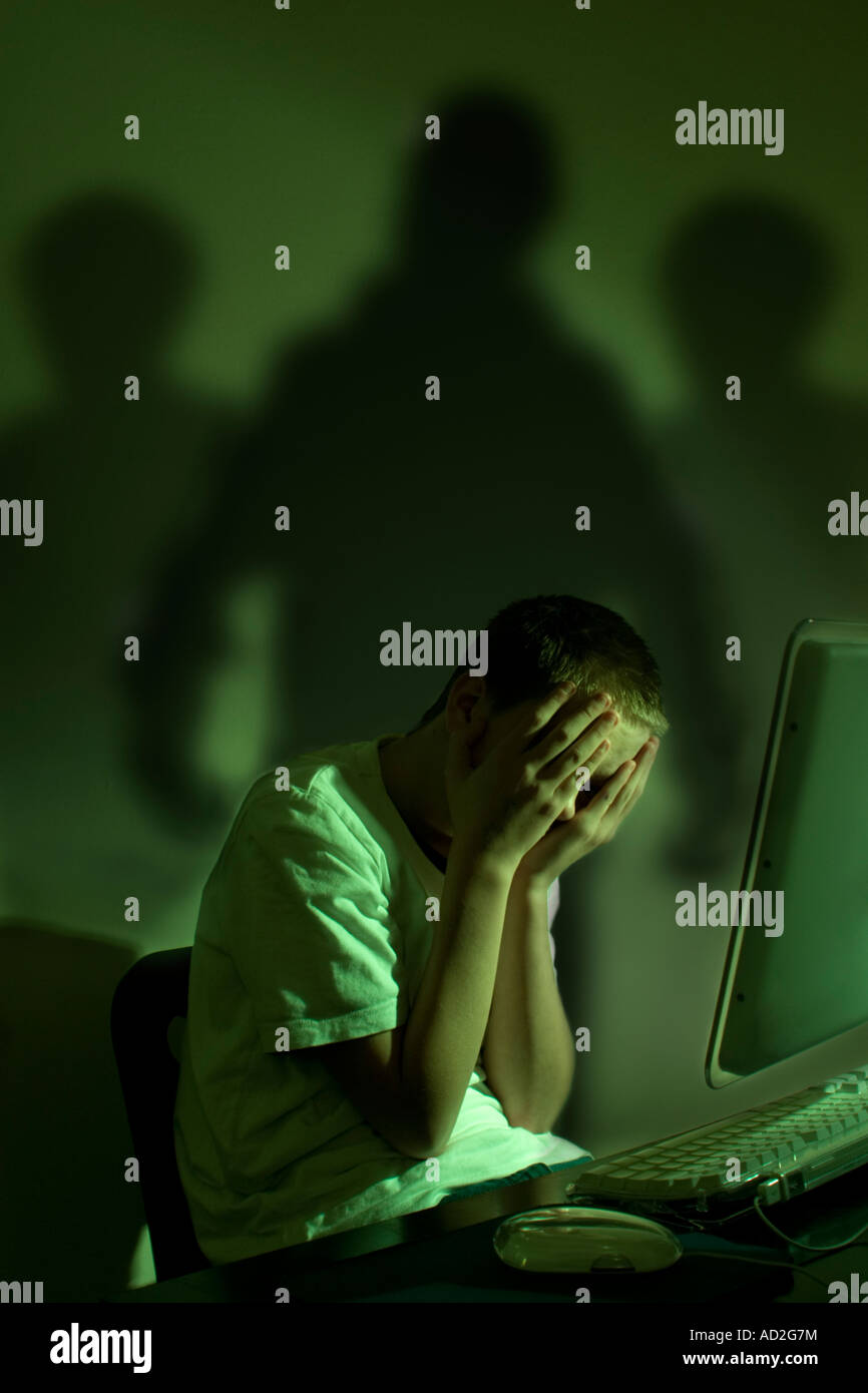 Cyber bullying concept  - Three shadows menace boy at computer Stock Photo