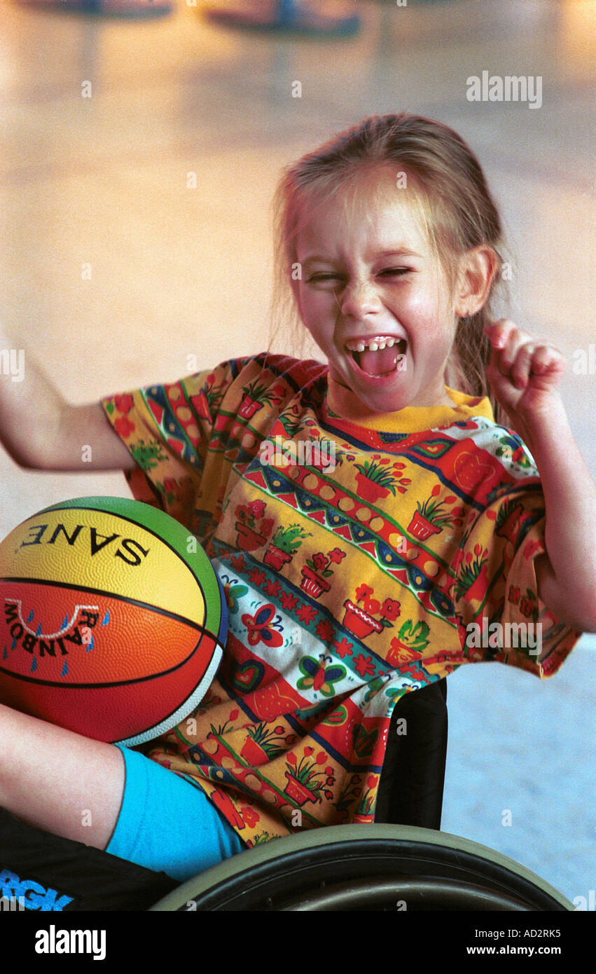 Happy child in wheelchair with ball,  expressing her victory Stock Photo