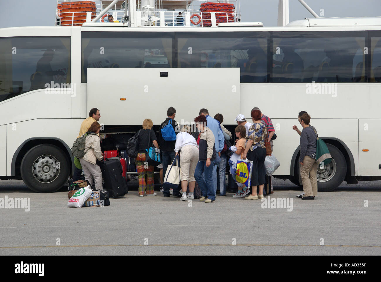 Passengers collect suitcase luggage from white unmarked coach bus at Greek Ferry Terminal in Port of Igoumenitsa on Ionian Sea Thesprotia.Greece EU Stock Photo