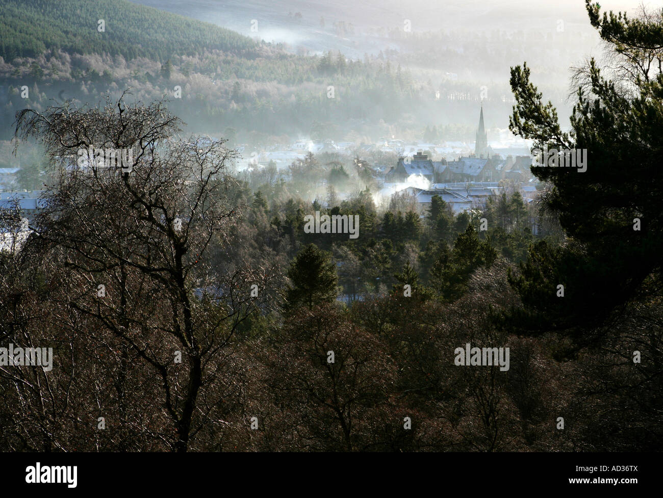 A moody landscape format image of Ballater, Scotland looking down from Craigendarroch in winter through trees. Stock Photo