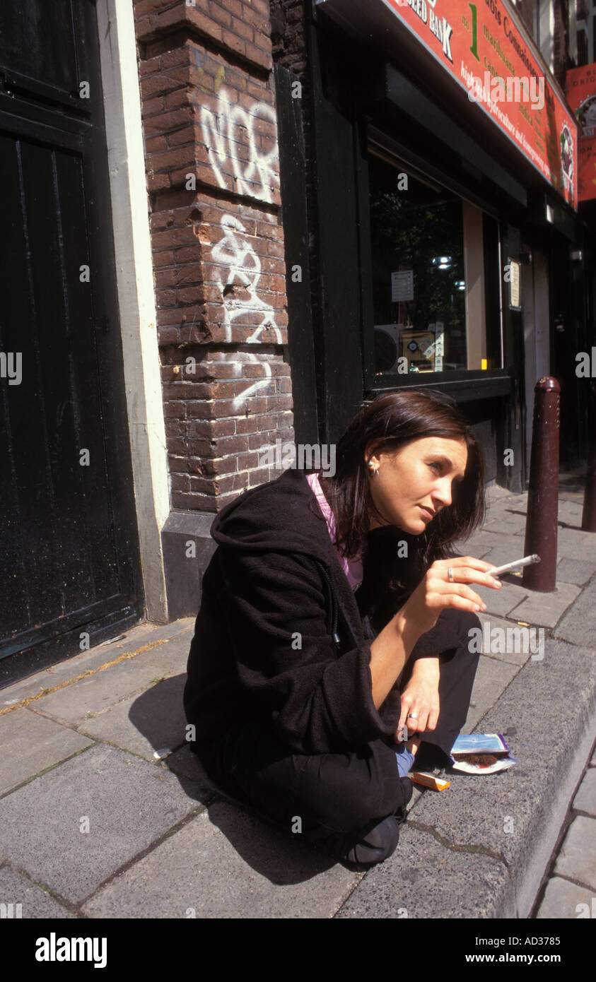 Woman smoking cannabis joint on the street outside  a cafe in Amsterdam. Stock Photo