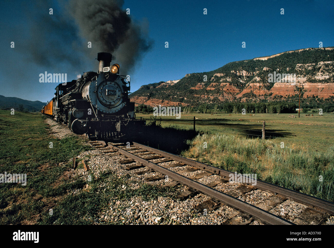 Old fashioned narrow gauge steam railroad travels down track in ...