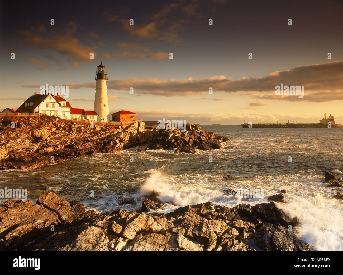 Ship passing Portland Head Lighthouse on coast of Maine at sunrise Stock Photo