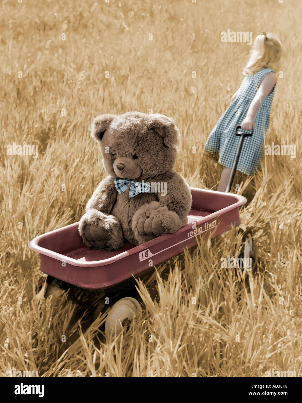 Hand colored photo of young girl pulling large plush bear through a