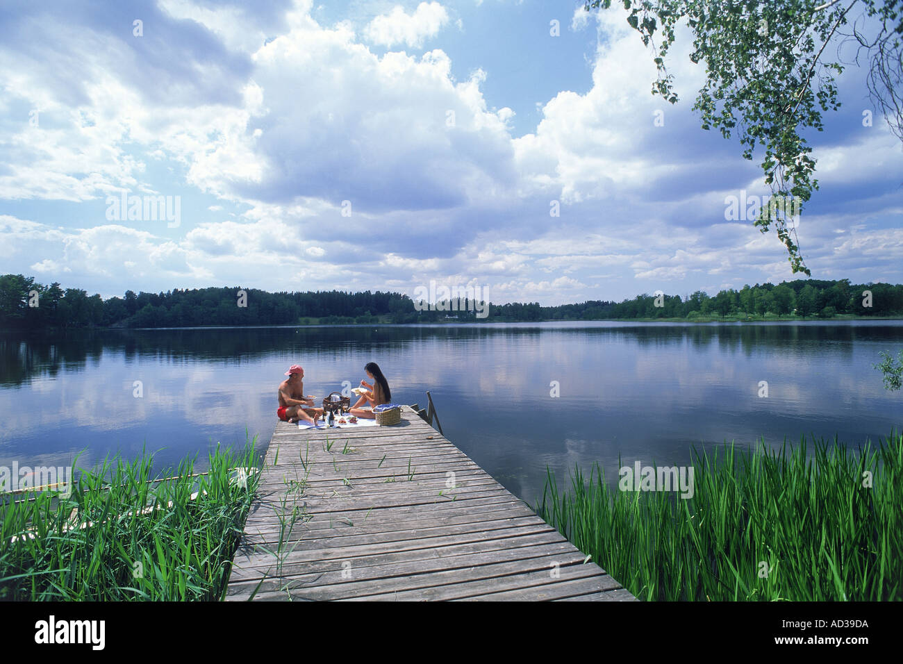 Couple having picnic on lake pier at Yxtaholm in Sweden Stock Photo