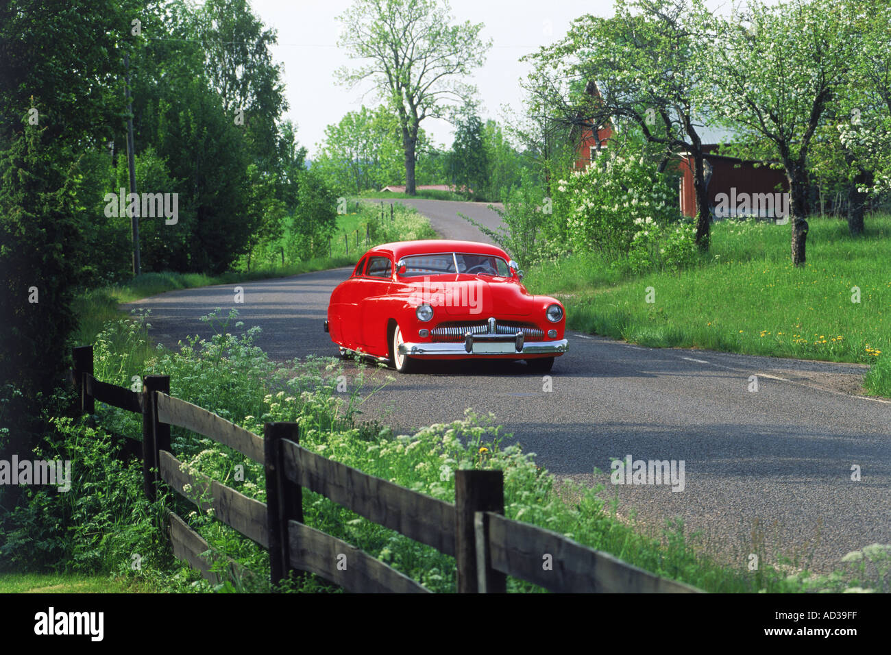Classic red car passing through Swedish countryside Stock Photo