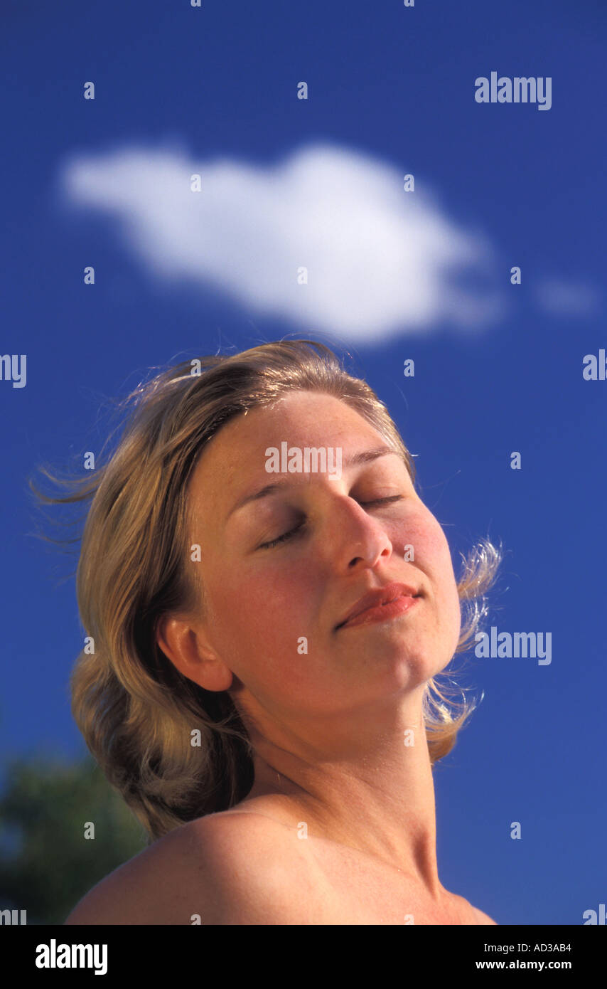 Swedish woman sunbathing under passing cloud and blue skies Stock Photo