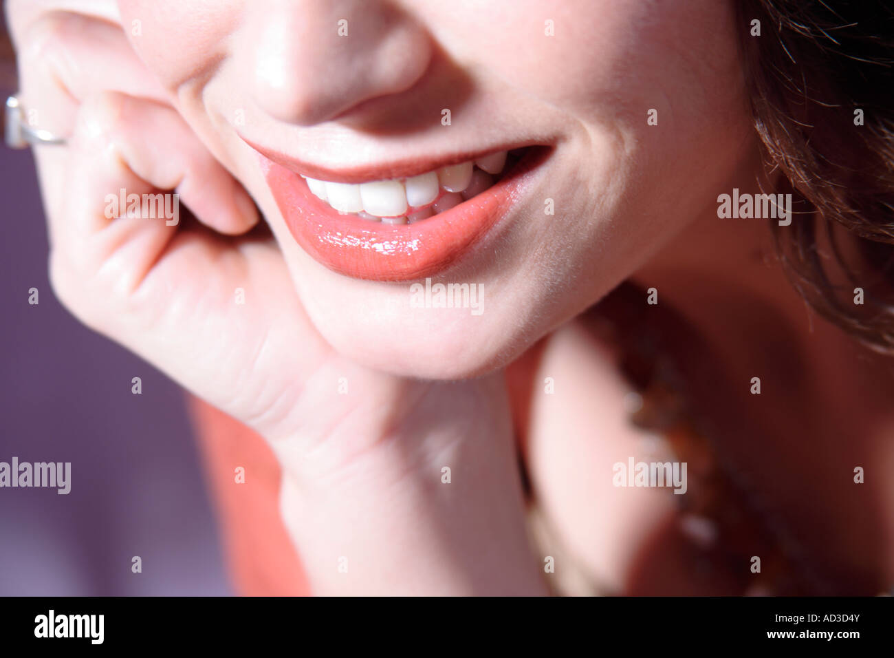 Face detail woman's mouth smiling, chin resting on hand, close up