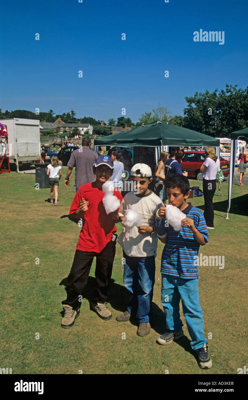 TILFORD SURREY UK July Three Asian teenagers enjoying candy floss during the annual summer fete Stock Photo