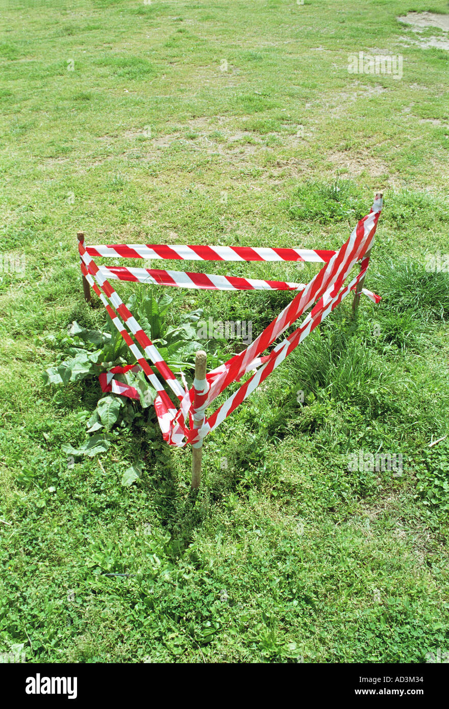 red white warning tape in triangle covering hole in park Stock Photo ...