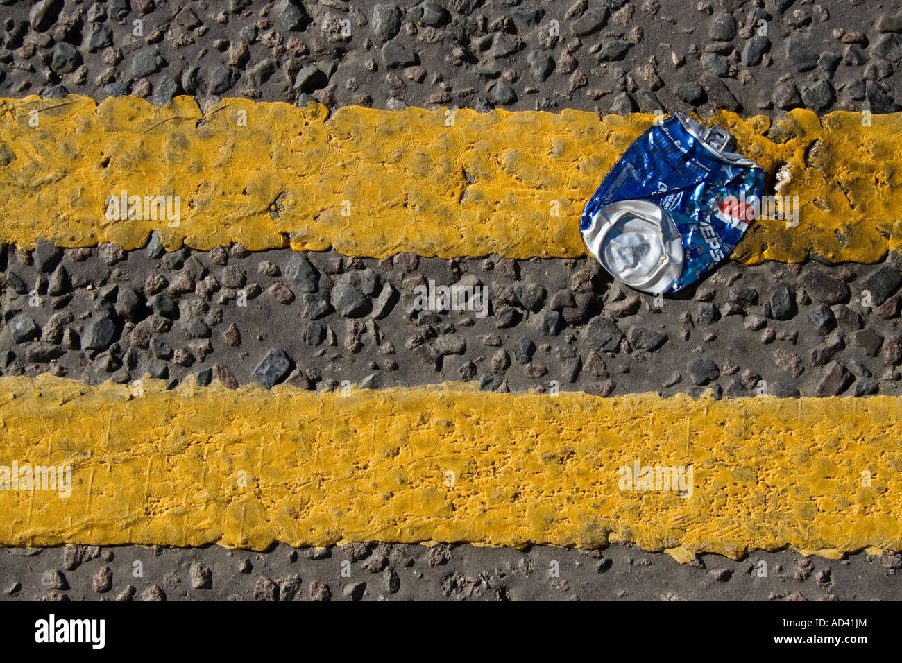 A blue soft drink can squashed into no parking double yellow road markings Stock Photo