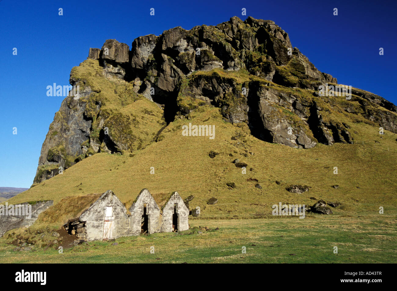 Southwest Iceland Old abandoned houses sit at the foot of a rock formation  Stock Photo