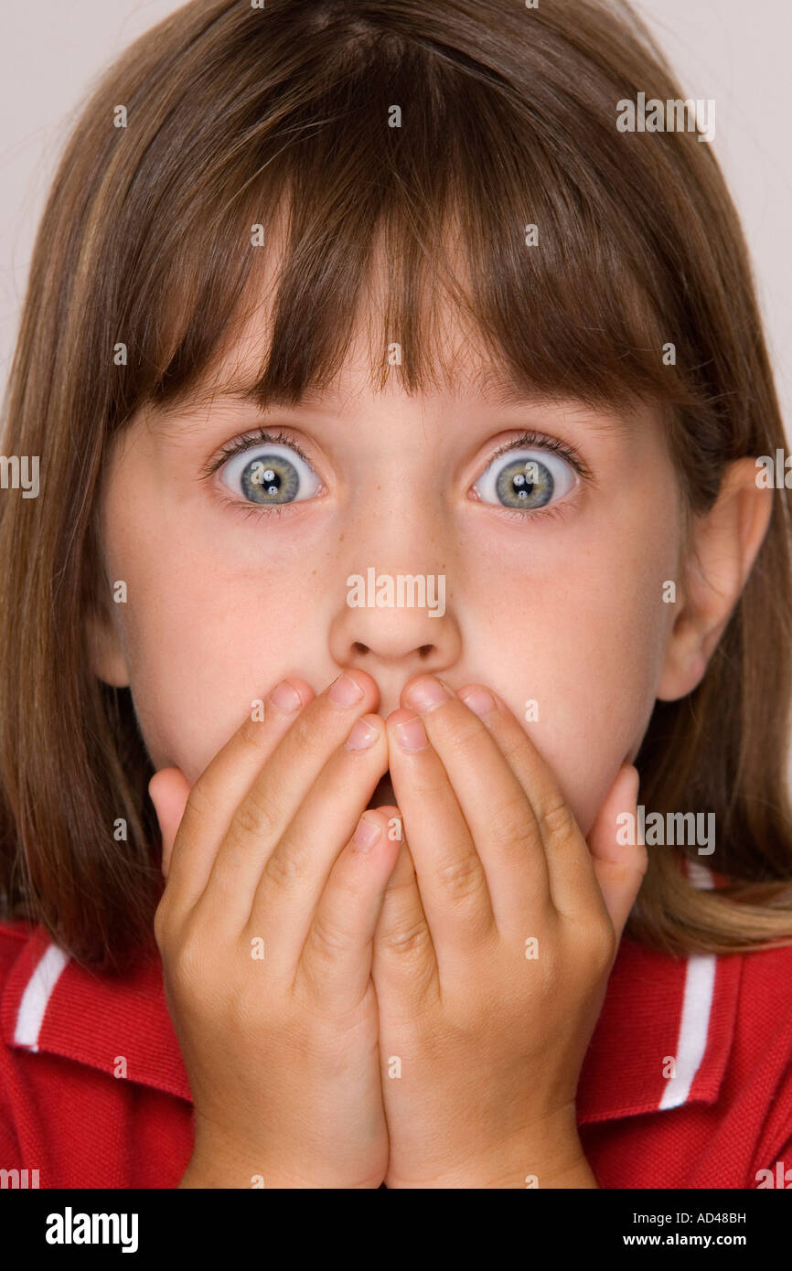 Tight cropped face of a scared young girl with hands covering