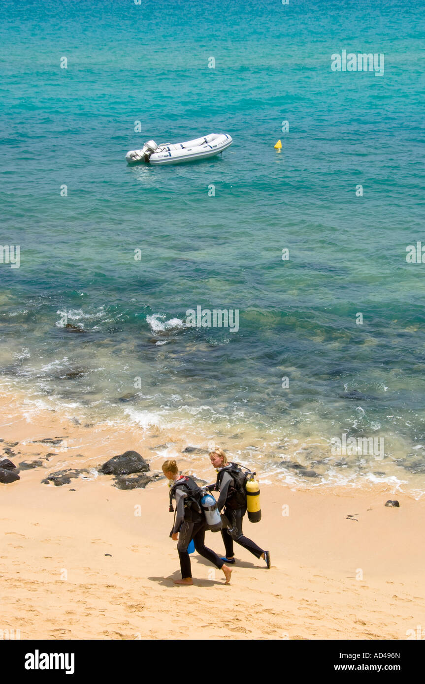 Two divers with equipment on their way to a dinghy, beach in Fuerteventura, Canary Islands