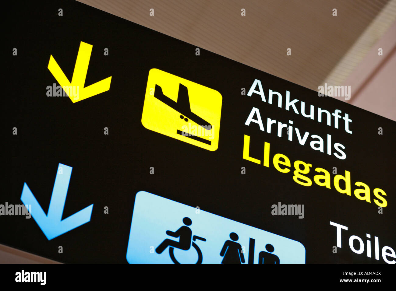 Multilingual airport sign, direction to arrivals, Malaga, Spain Stock Photo