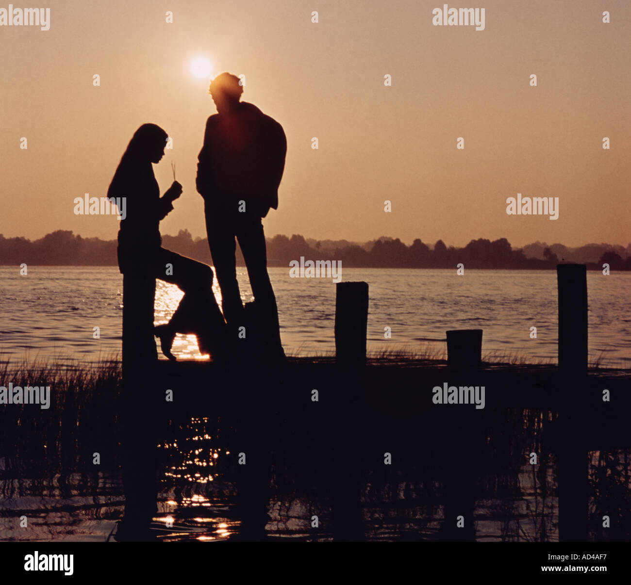 romantic young couple enjoying sunset from a wooden dock on Florida lake Stock Photo