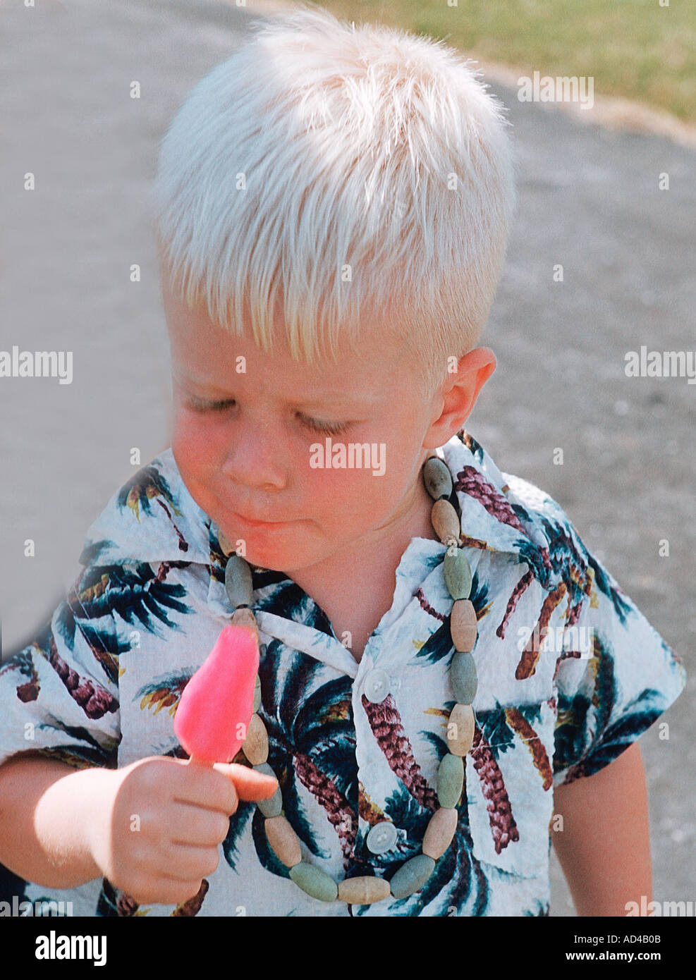 small boy enjoying the taste of a pink pop sickle on a summer day Stock Photo