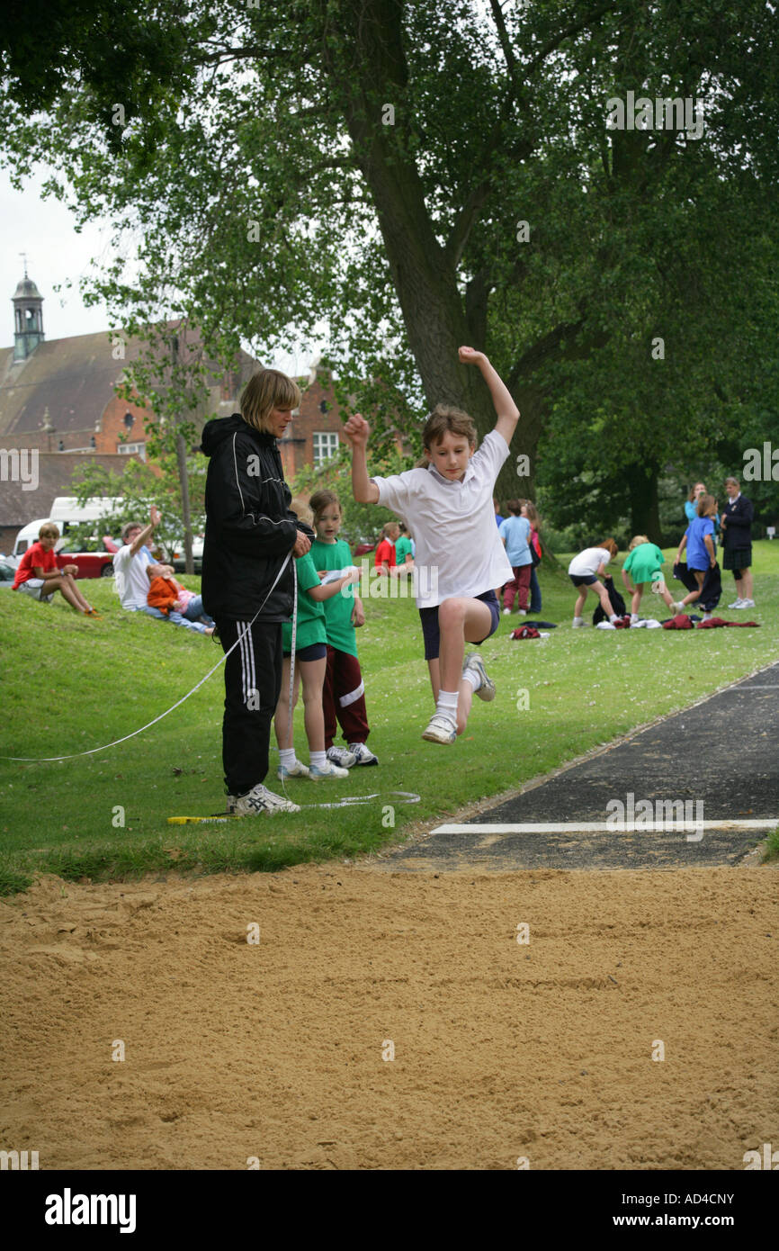 Eight year old pupil taking part in long jump event during sports day