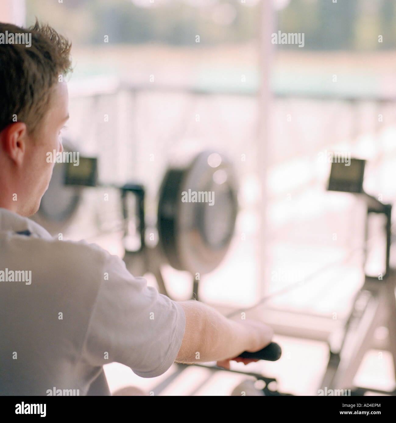Over the shoulder view of man using rowing machine Stock Photo