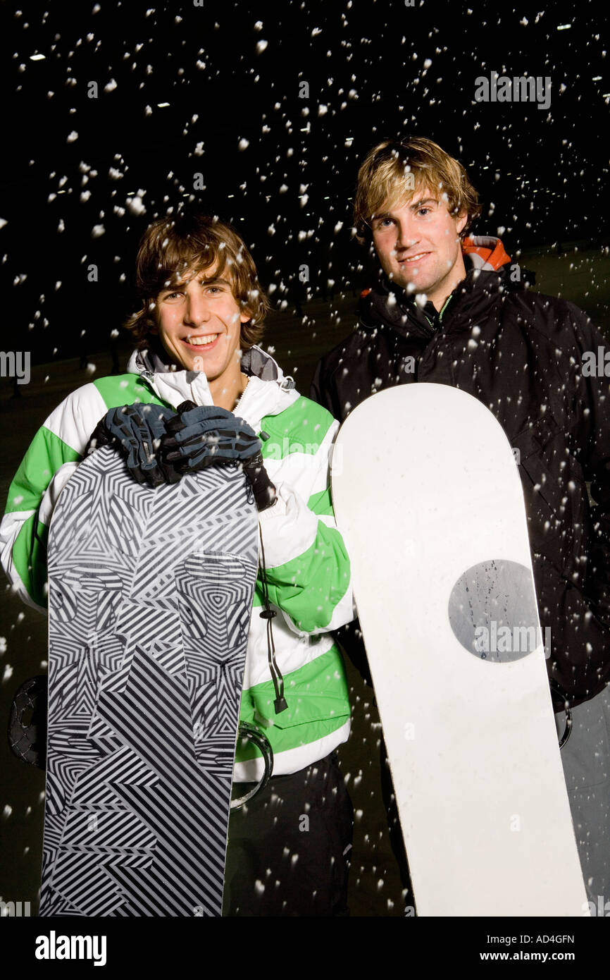 Two young men holding snowboards whilst standing in the snow Stock Photo