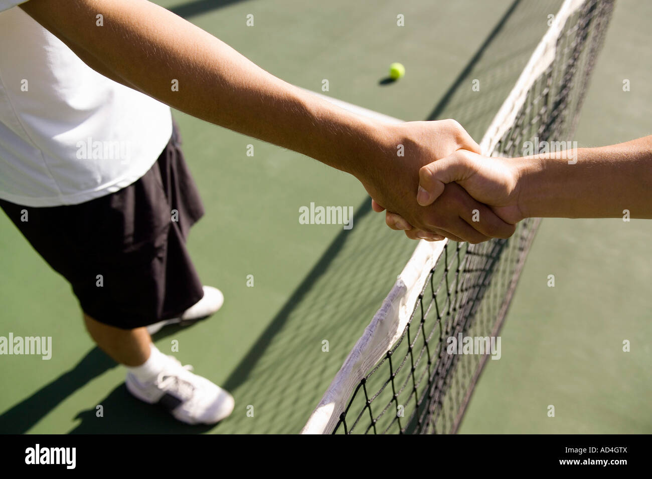 Two tennis players shake hands across the net Stock Photo