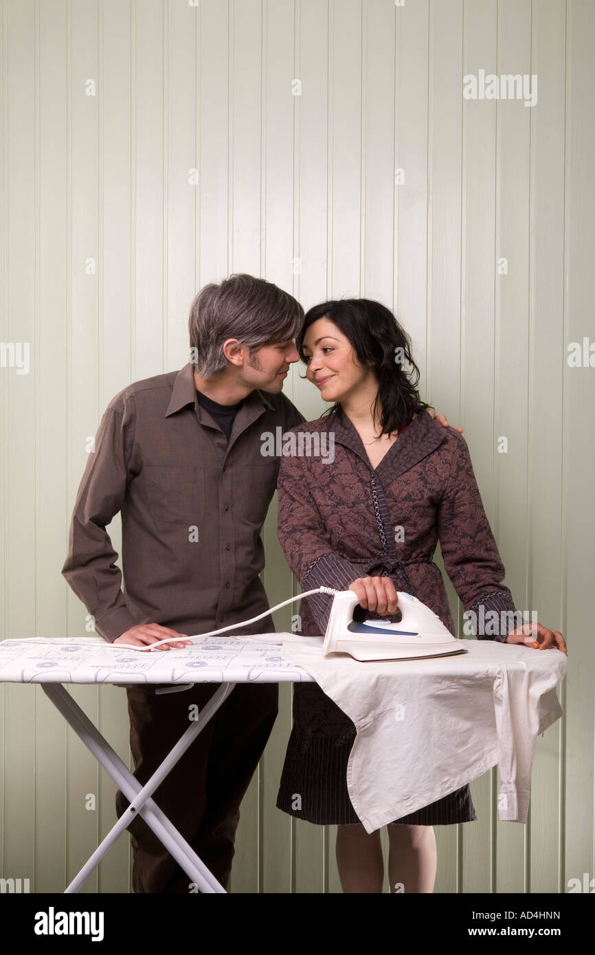 A couple kissing whilst ironing Stock Photo