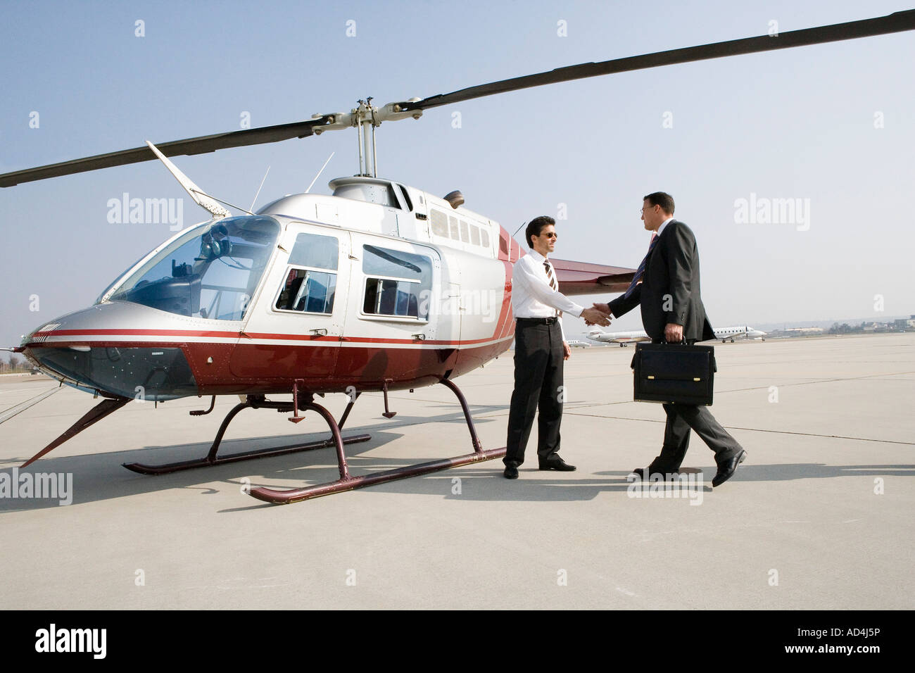 Businessmen shaking hands by a helicopter Stock Photo Alamy