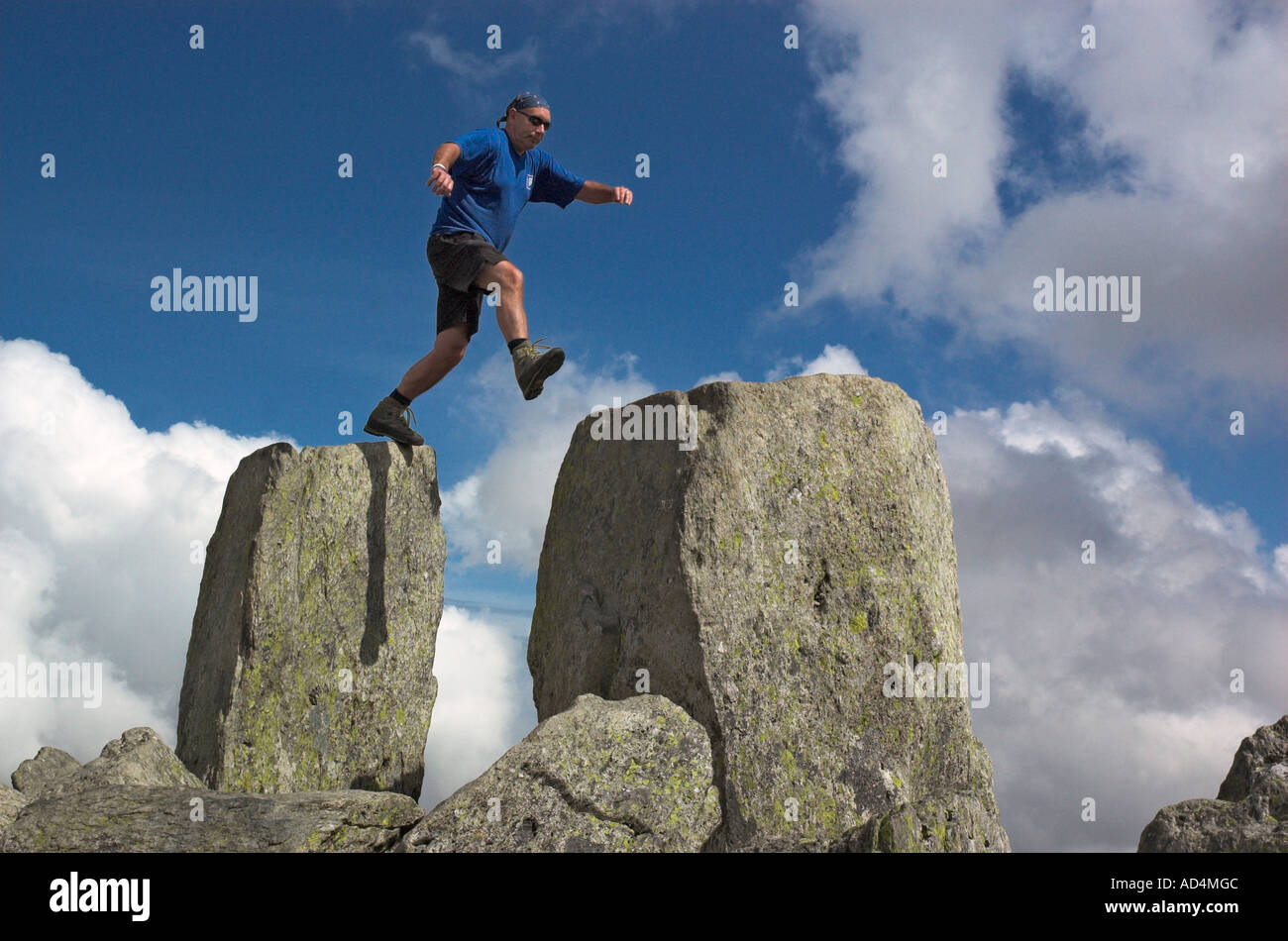 A climber jumping on Adam and Eve on the summit of Tryfan in Snowdonia