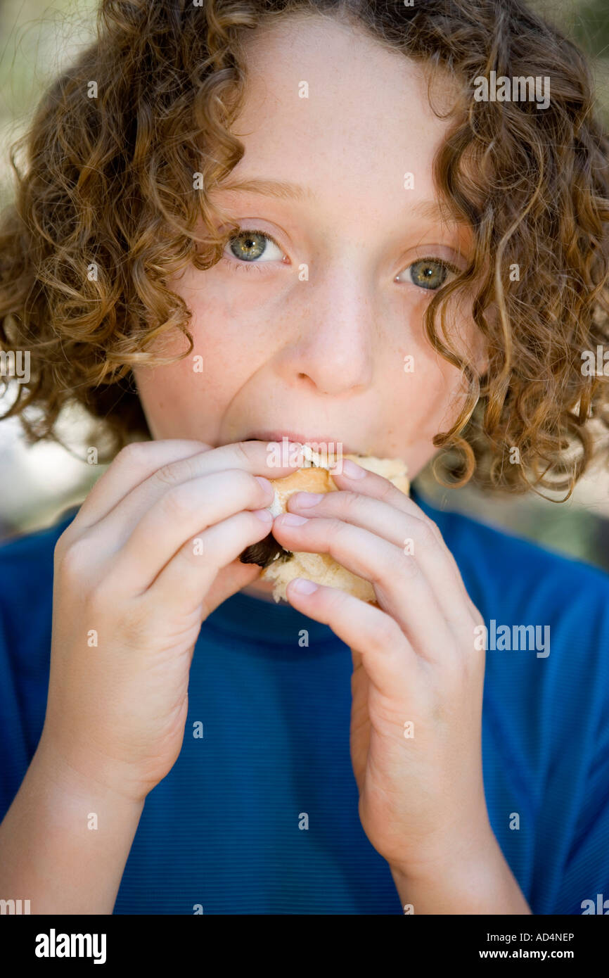 A young boy eating a sausage in a bread roll Stock Photo Alamy