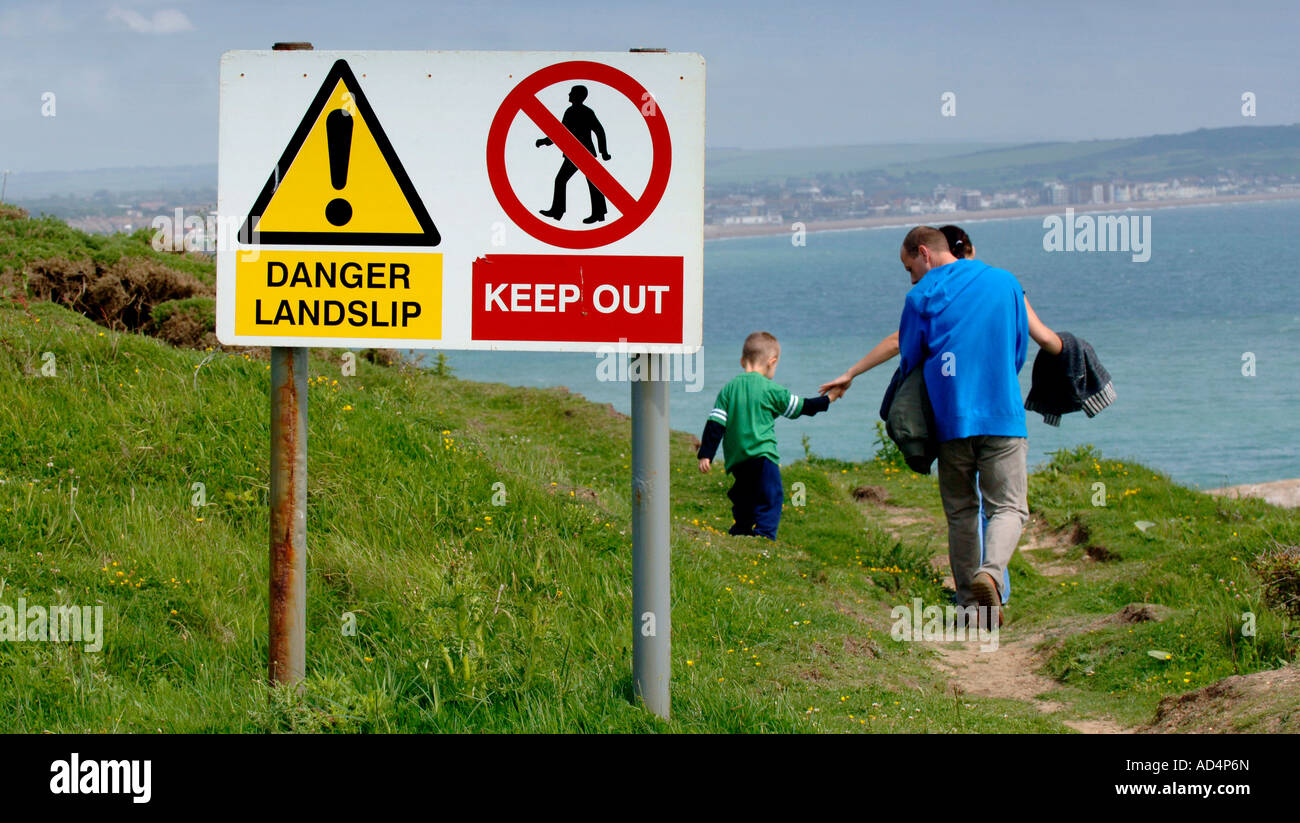 A family appear to walk beyond the danger signs on a cliff top footpath. Picture by Jim Holden. Stock Photo