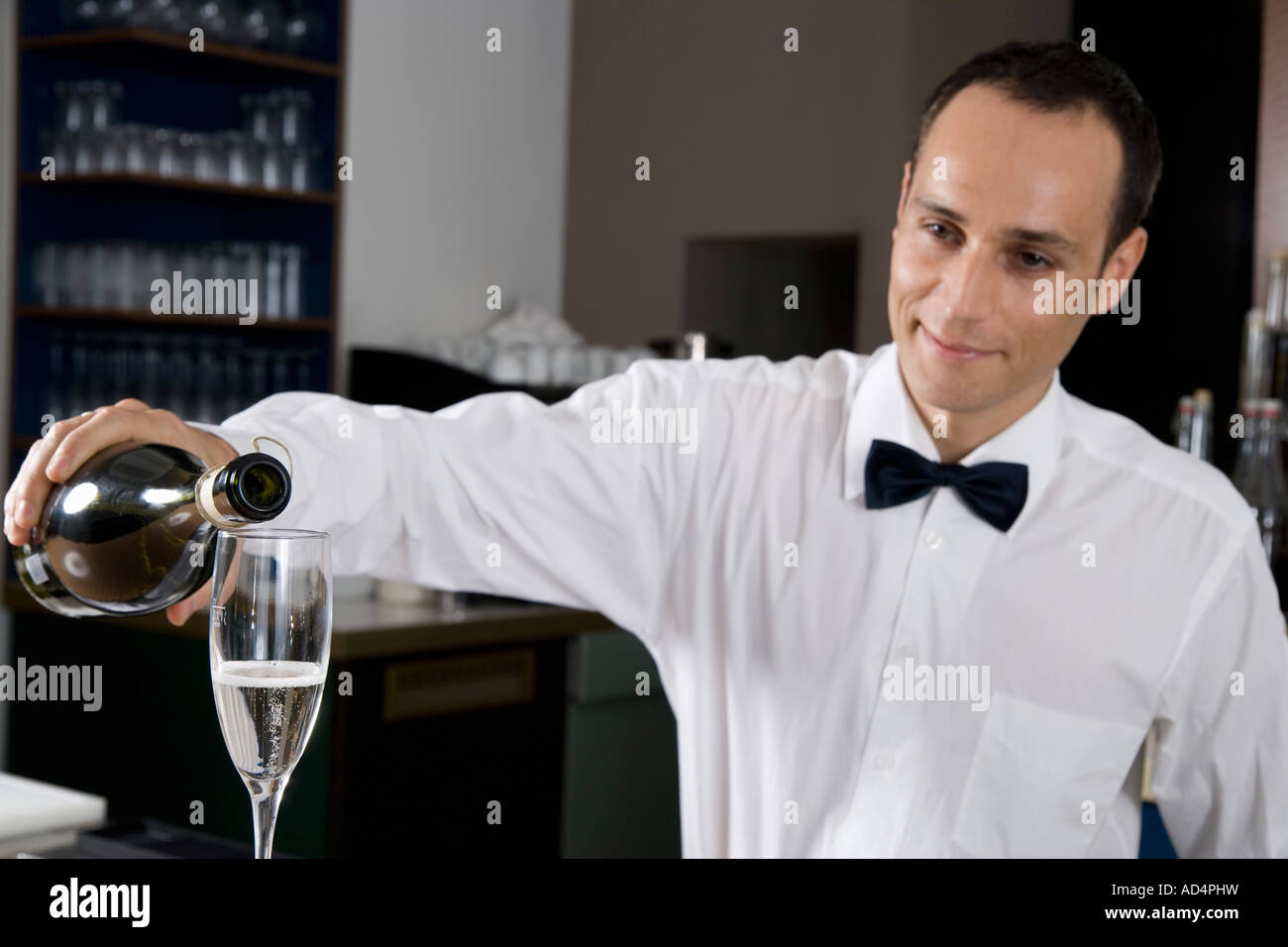 A bar tender pouring a glass of champagne Stock Photo