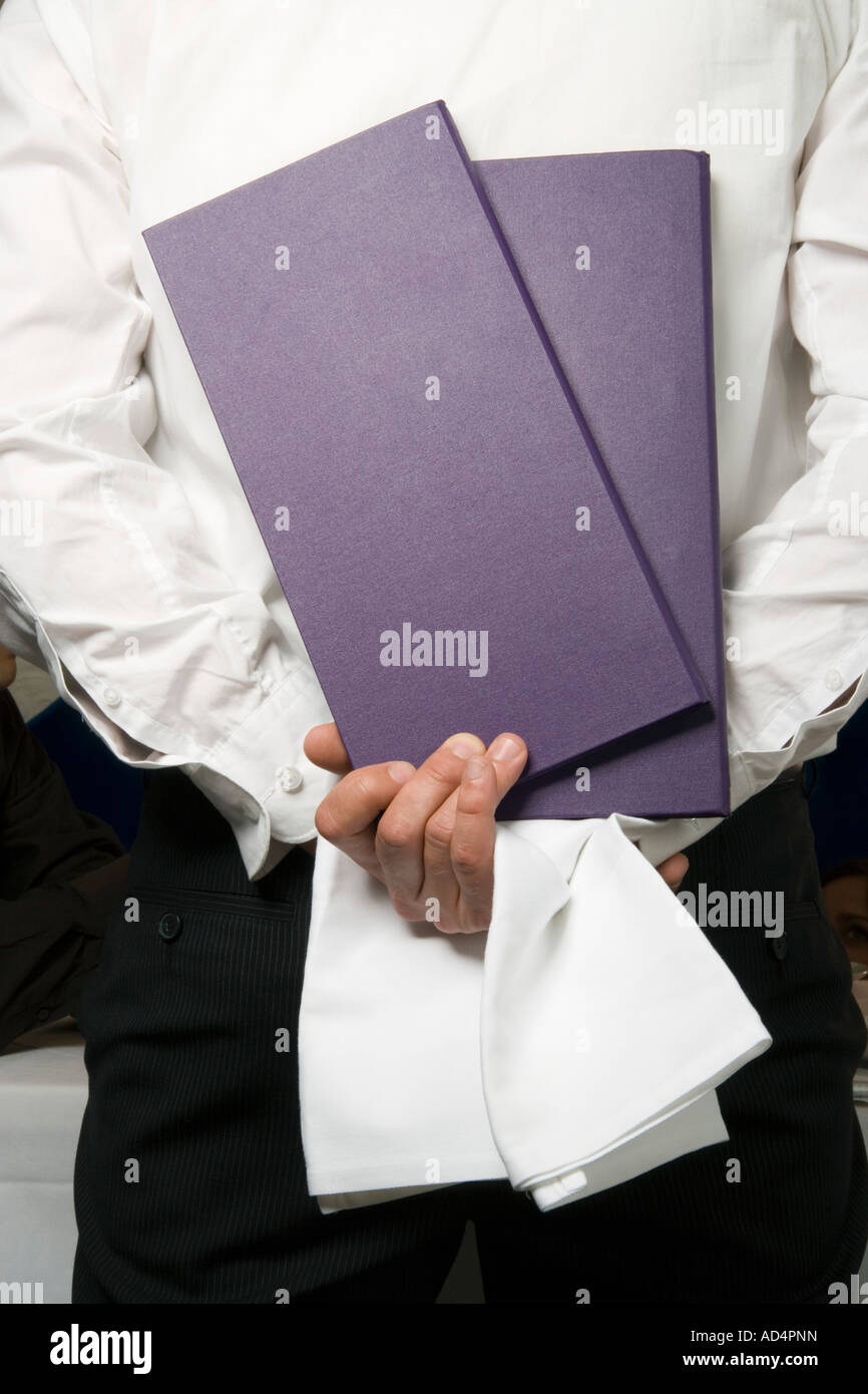 A waiter holding menus behind his back Stock Photo