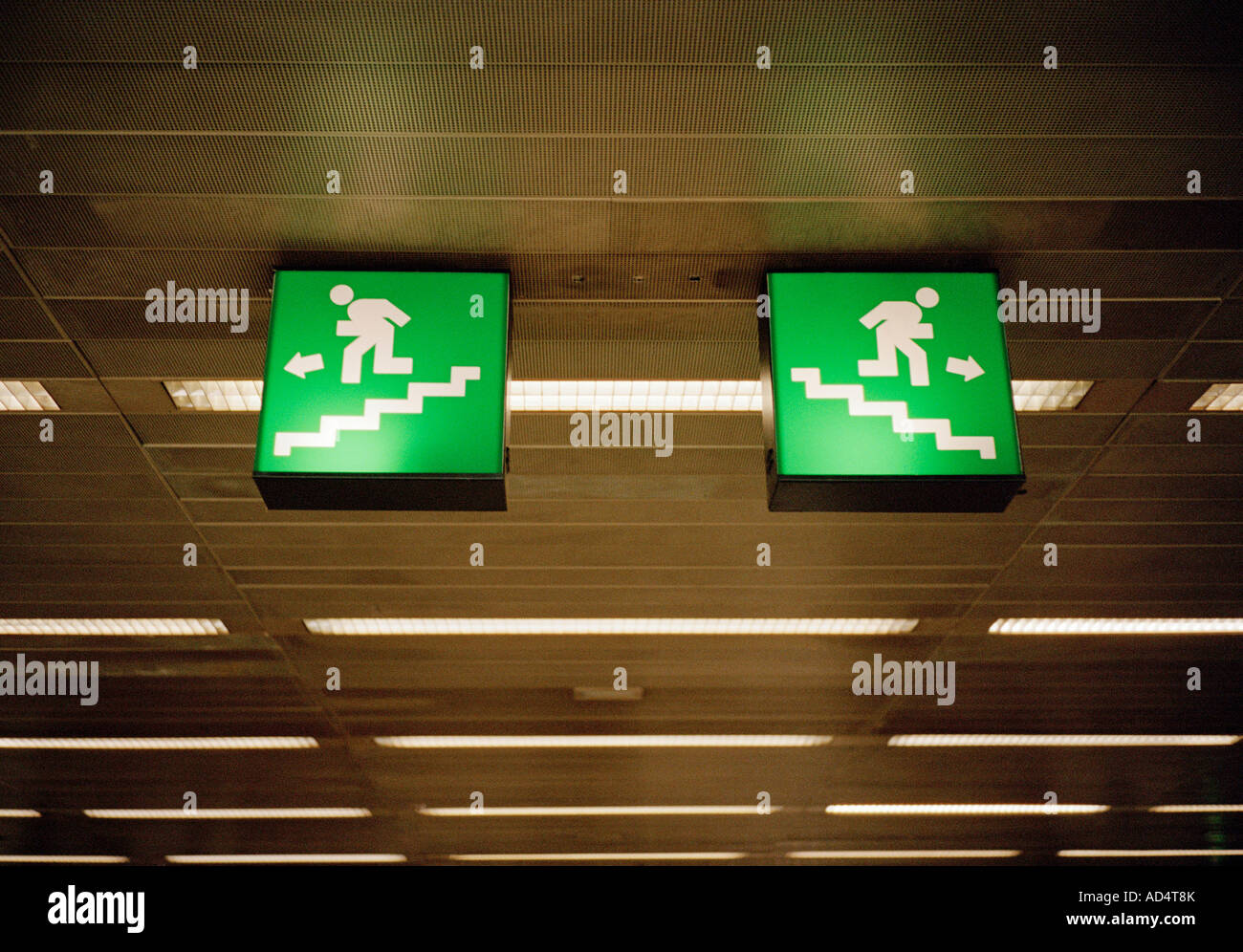 Illuminated emergency exit signs on a ceiling Stock Photo