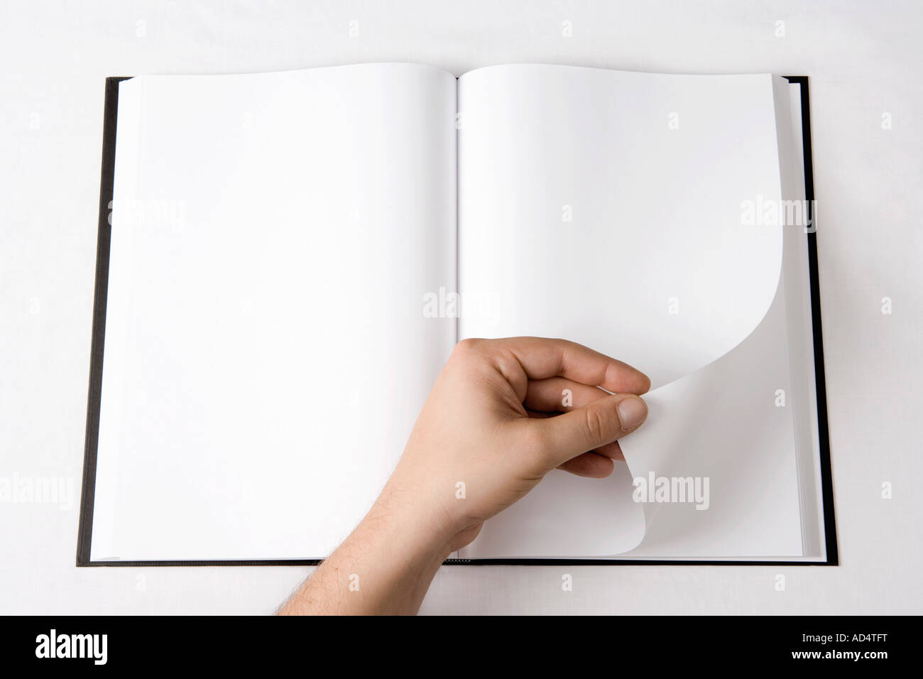 Detail of a man turning a page of a blank book Stock Photo