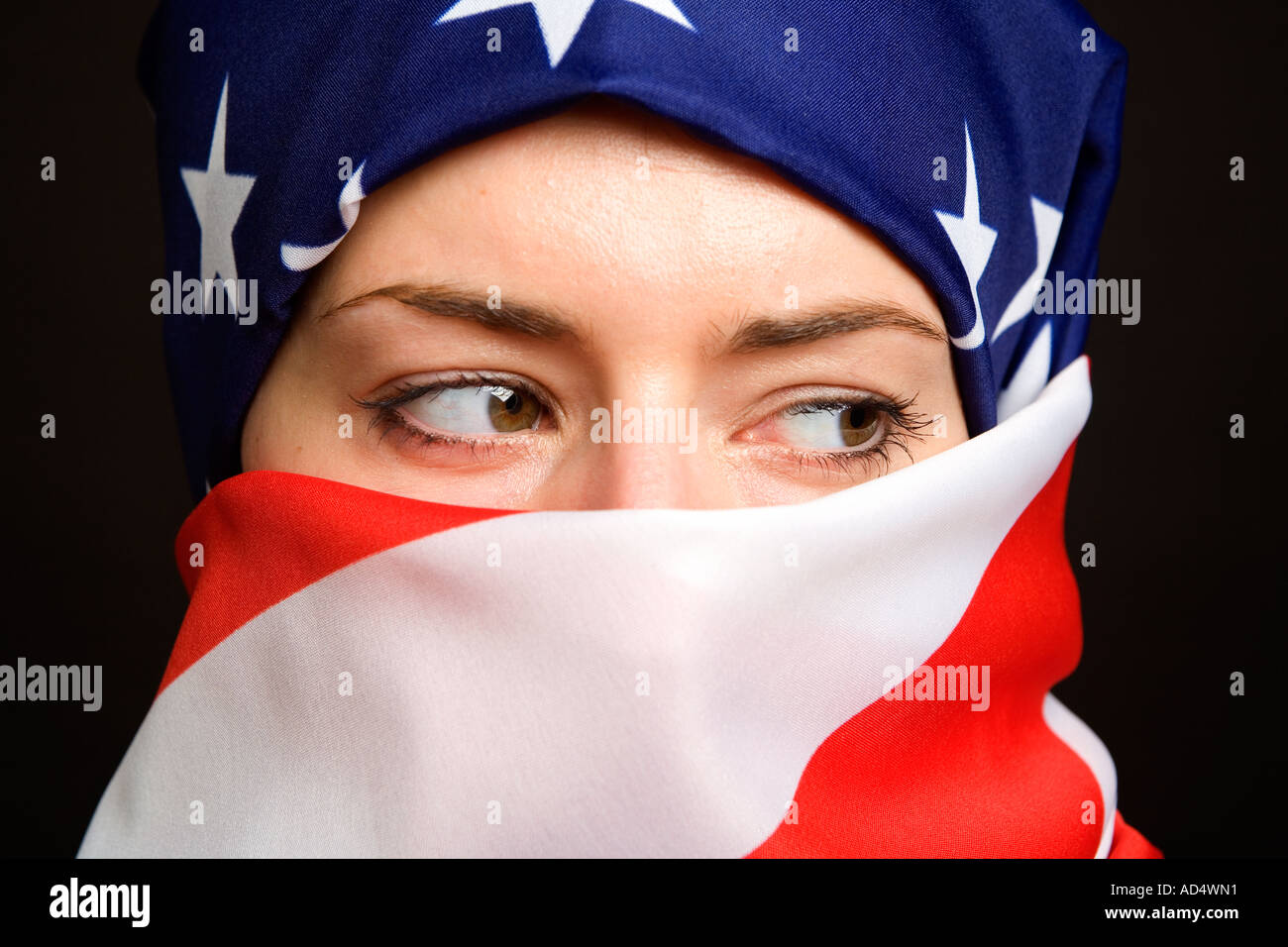 Muslim woman wearing an American USA US  flag as a  hijab burka with a black background Stock Photo