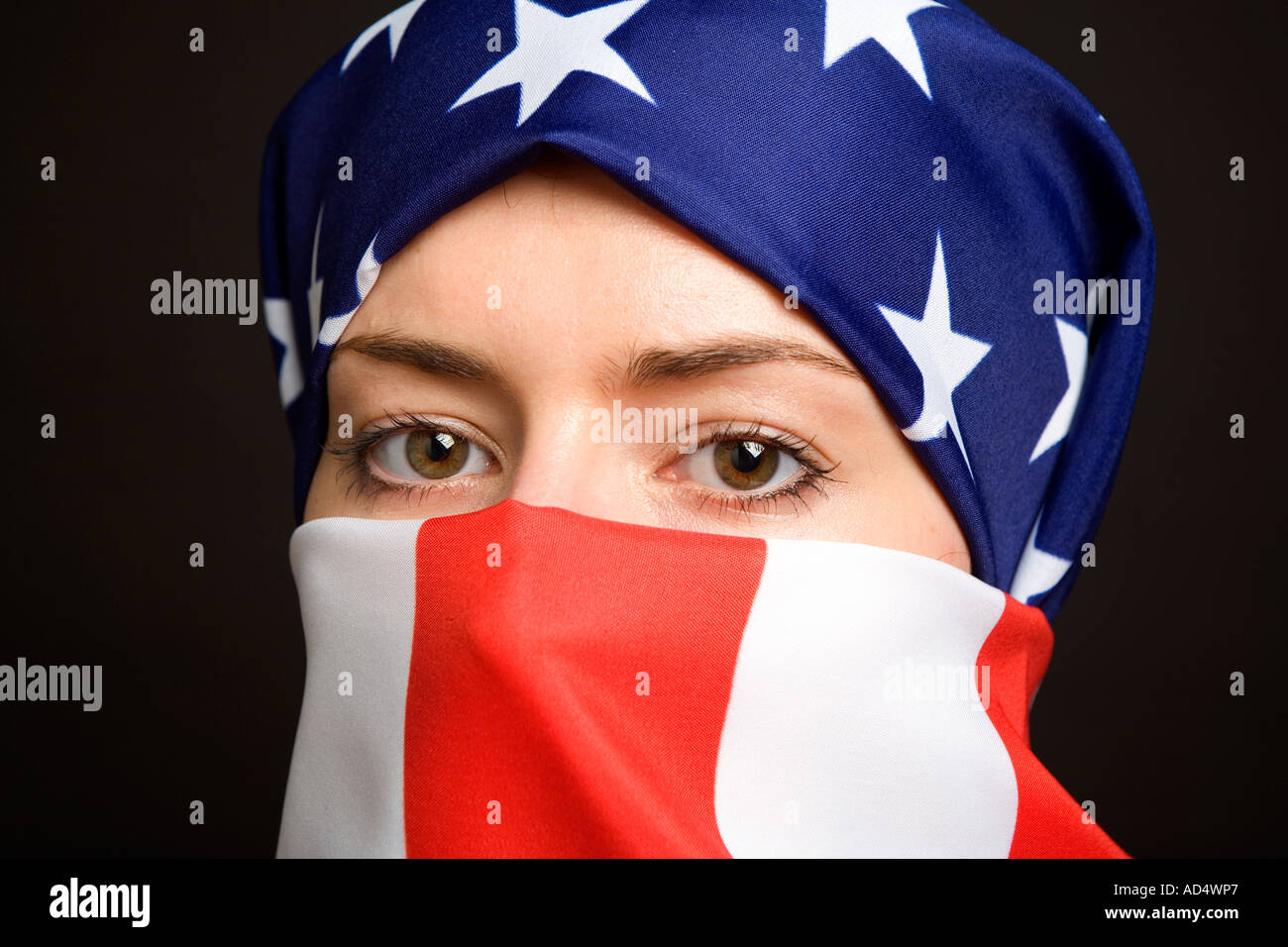 Muslim woman wearing an American USA US  flag as a  hijab burka with a black background Stock Photo