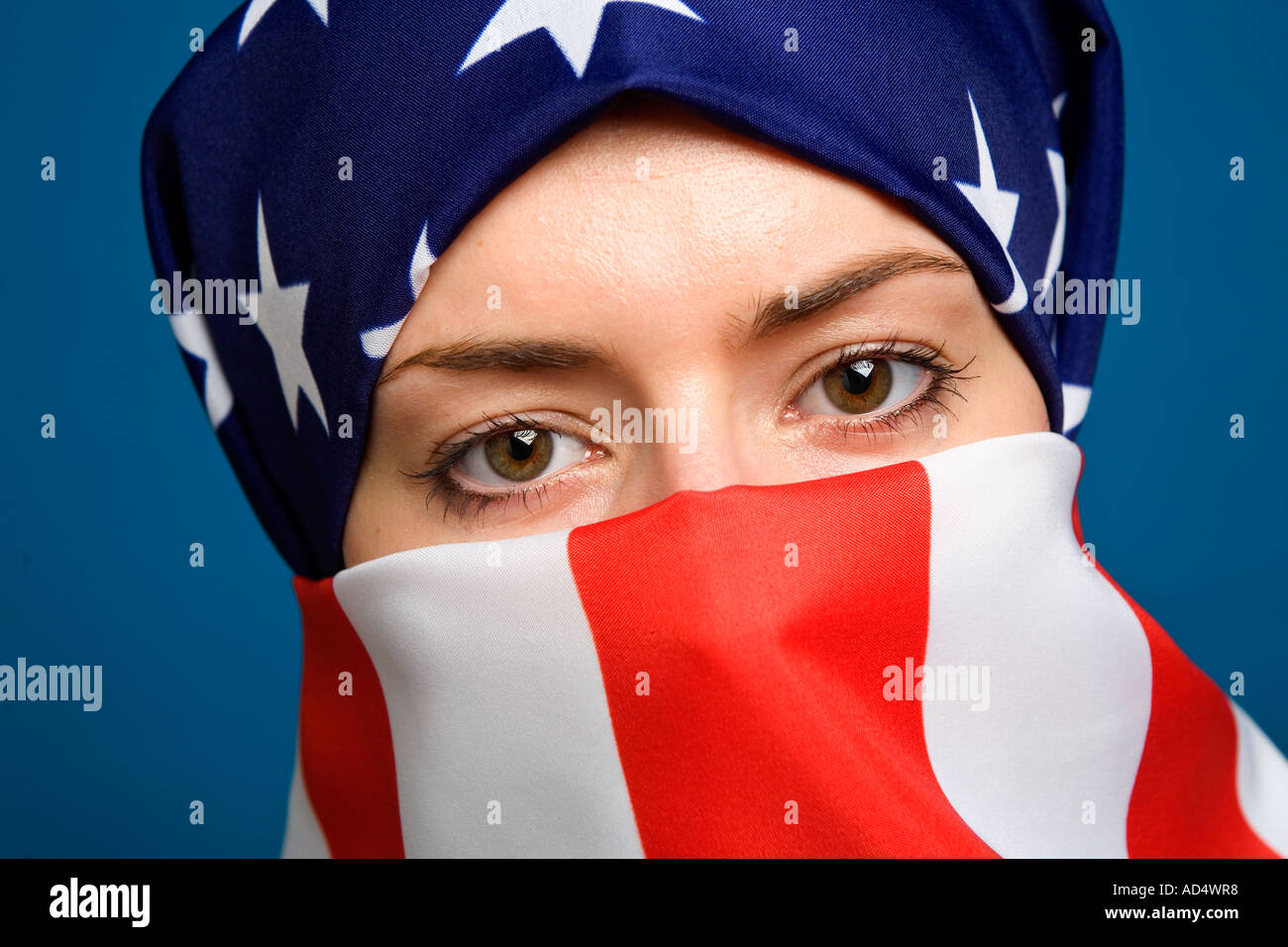 Muslim woman wearing an American USA US  flag as a  hijab burka with a blue background Stock Photo